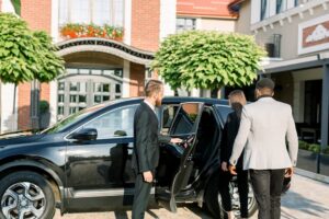 chauffeur opening door for business men