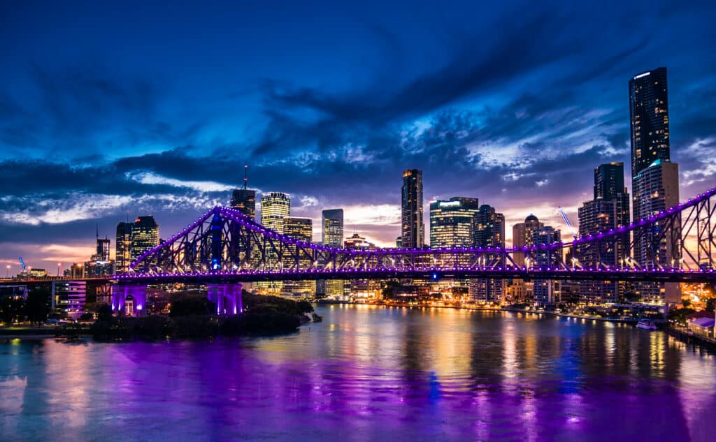 night time panorama of Brisbane city with purple lights on Story Bridge, Australia